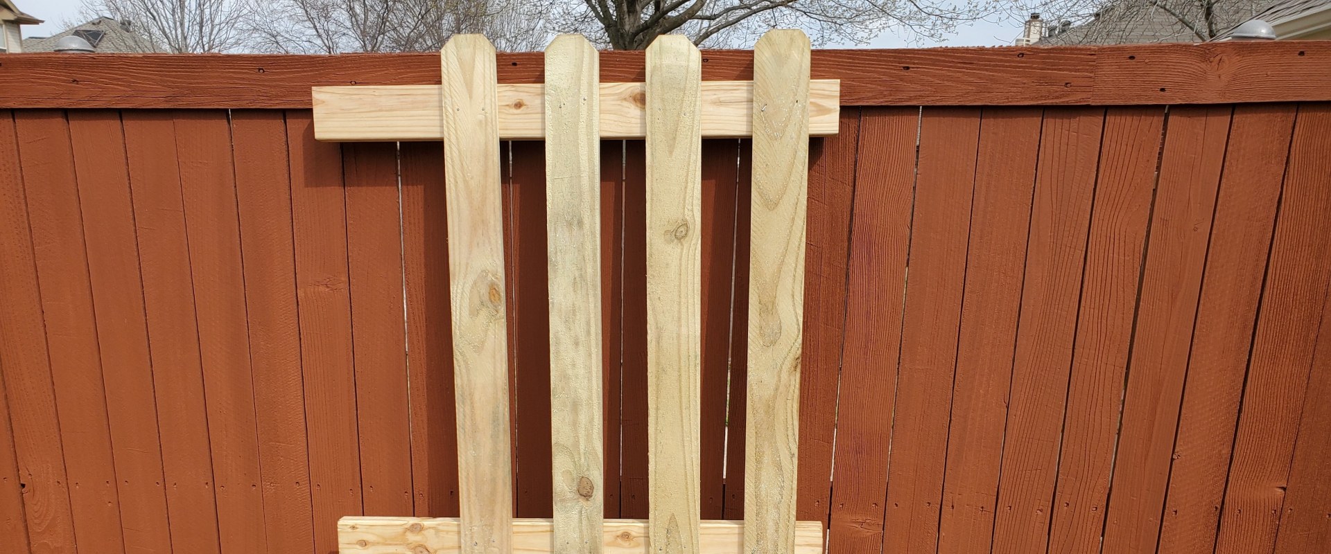New cedar fence pickets being installed to replace old weathered panels